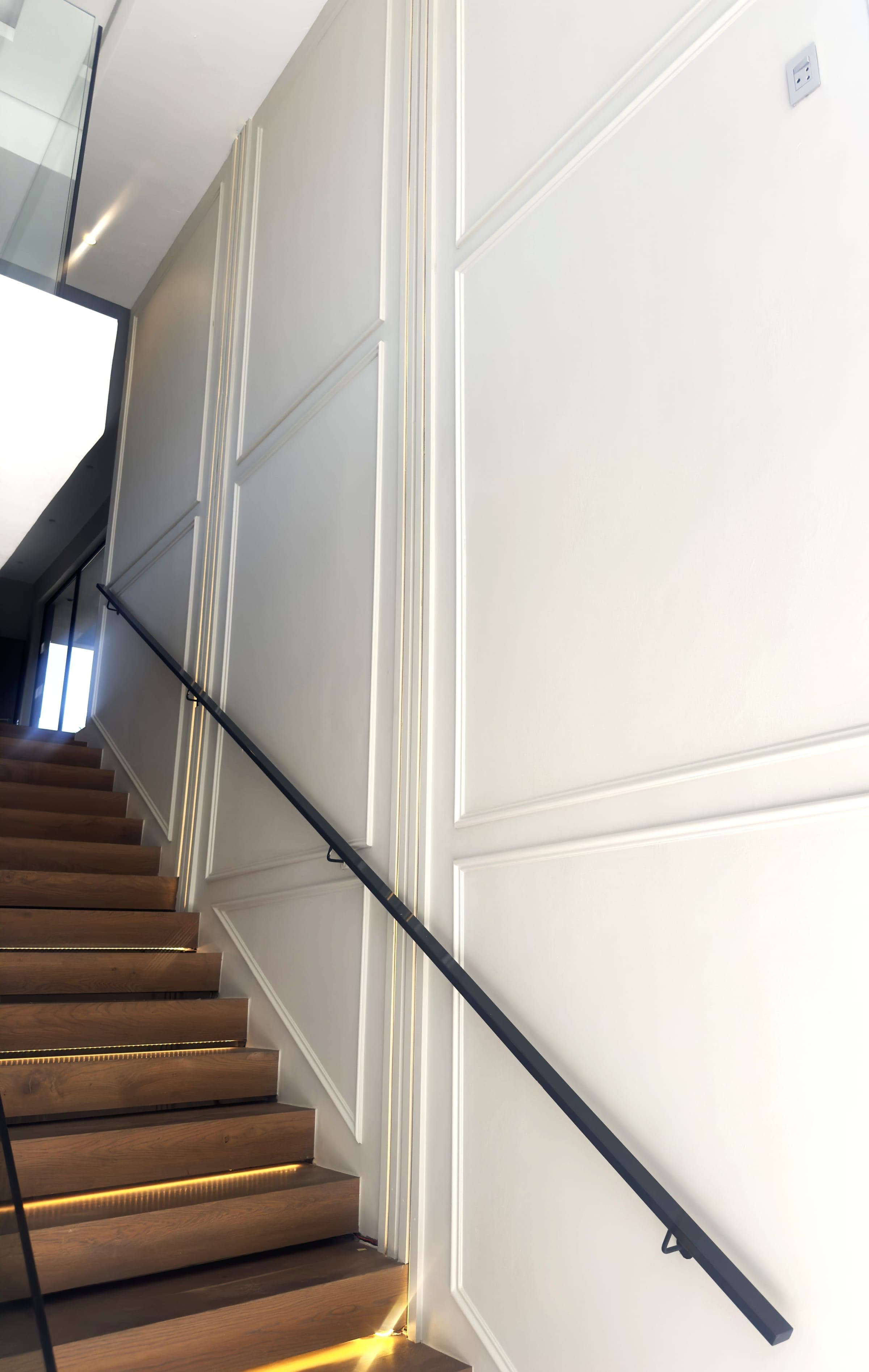 Staircase panelling, LED-lit steps and black handrail